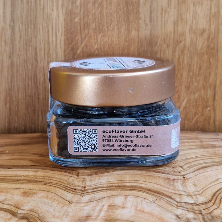 Schwarzer Pfeffer aus Madagaskar – naturbelassen, sonnengetrocknet und handverlesen, in einem Glas mit kupferfarbenen Deckel auf einem Holzbrett präsentiert von ecoflavor.