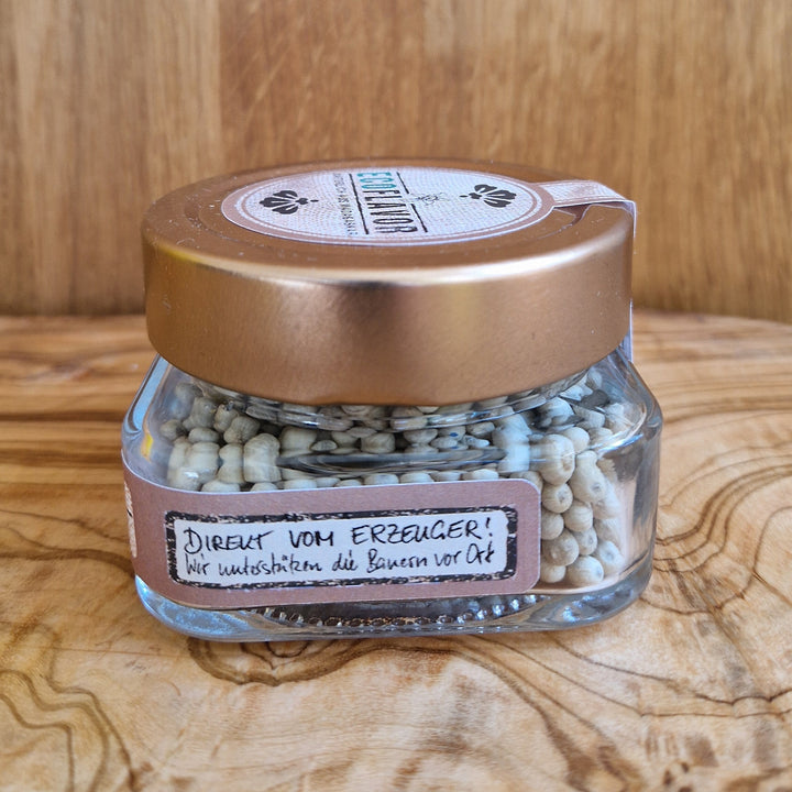 Weißer Premium Pfeffer aus Madagaskar – handverlesen, naturbelassen und sonnengetrocknet, in einem Glas mit kupferfarbenen Deckel stilvoll angerichtet.