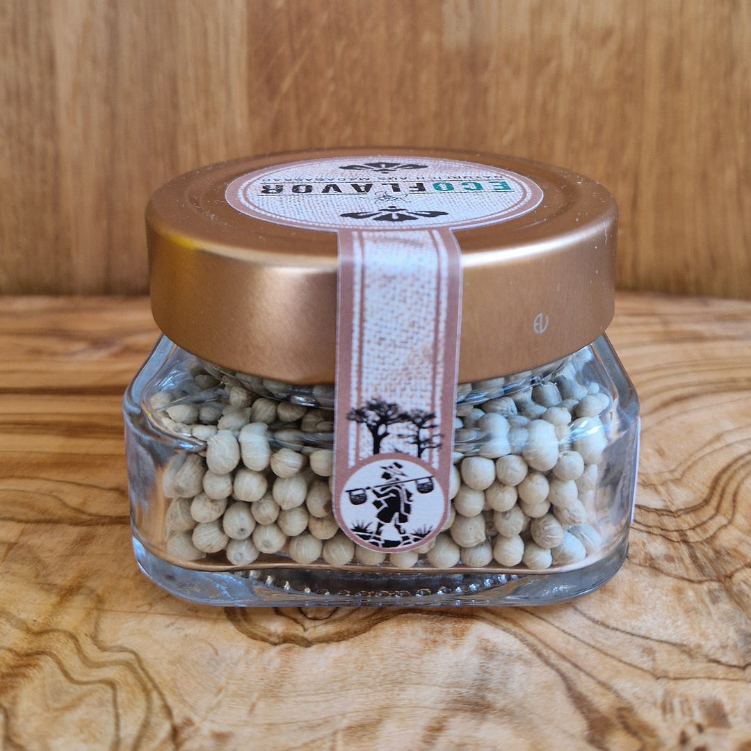 Weißer Premium Pfeffer aus Madagaskar – handverlesen, naturbelassen und sonnengetrocknet, in einem Glas mit kupferfarbenen Deckel stilvoll angerichtet.